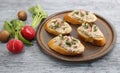 Mushroom Pate on bread slices garnished with red radishes, brown plate, blue surface