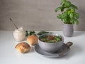 Mushroom soup in a deep bowl and dark flour bread rolls on a white table. Pot with fresh basil. Royalty Free Stock Photo