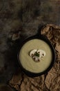 Mushroom soup with 3 mushrooms on top on rusty brown background and wrinkled texture