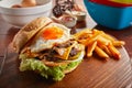 Mushroom Swiss beef burger with sunny egg and fries served in a dish isolated on wooden background side view Royalty Free Stock Photo