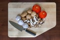 Mushrooms Tomatoes Garlic Cloves Kitchen Knife on Cutting Board Royalty Free Stock Photo