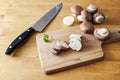 Mushrooms whole and sliced on a wooden cutting board and a kitchen knife, preparation for cooking a healthy vegetarian meal, copy Royalty Free Stock Photo