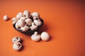 Mushrooms in a wooden bowl on an orange background. The small white champignon in a plate and scattered near it Royalty Free Stock Photo