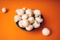 Mushrooms in a wooden bowl on an orange background. The small white champignon in a plate and scattered near it Royalty Free Stock Photo