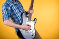 Music and art. The guitarist plays the electric guitar on a yellow isolated background. Playing guitar. Horizontal frame Royalty Free Stock Photo