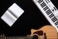 Music background with acoustic guitar, notepad and music keys on black. Royalty Free Stock Photo
