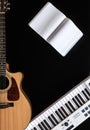 Music background with acoustic guitar, notepad and music keys on black. Royalty Free Stock Photo