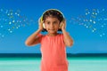 Music, childhood and technology concept- little indian girl with headphones over sea view backgroundound with musical notes Royalty Free Stock Photo