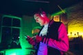 Cinematic portrait of handsome young man using devices, gadgets in neon lighted interior. Youth culture, bright colors