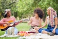 Music, comic and friends on picnic in a park with food and singing with a guitar together in summer. Funny, playful and Royalty Free Stock Photo