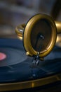 Music concept in vintage style. Close-up, vintage gold gramophone record player, read head with a needle, black record. Selective Royalty Free Stock Photo