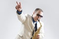 Music Concepts and Ideas. Portrait of Hadnsome Male Saxophone Player Showing V Sign Whilst Playing