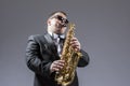 Music Concepts. Portrait of Mature Expressive Caucasian Saxophone Player in Sunglasses Playing the Saxophone in Studio