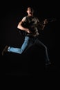 Music and creativity. Handsome young man in a T-shirt and jeans, jumping with an electric guitar, on a black isolated background.