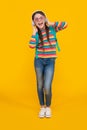 Music education. Teenage girl singing along to music after school yellow background, music