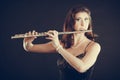 Woman playing transverse flute on black.