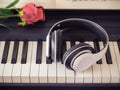 Music and entertainment concept.Music headphone on piano keyboard with red rose.vintage filtered Royalty Free Stock Photo