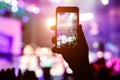 Music fans takes picture of stage in concert on smartphone. Royalty Free Stock Photo