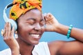 Music, freedom and headphones with a black woman outdoor on a blue wall background enjoying a track. Radio, relax and Royalty Free Stock Photo