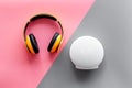 Audio listening with wireless headphones and portable speakers on pink and gray background top view