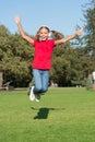 Music of happiness. Happy little child jump high on green grass. Small girl enjoy listening to music in modern