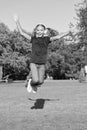 Music of happiness. Happy little child jump high on green grass. Small girl enjoy listening to music in modern