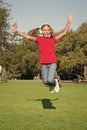 Music of happiness. Happy little child jump high on green grass. Small girl enjoy listening to music in modern