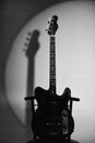 Music and hard rock concept. Electric guitar stands on dark red chair. Guitar in black Royalty Free Stock Photo