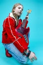 Music Ideas and Concepts. Caucasian Guitar Player Posing and Playing Electro Guitar Sitting In Fashionable Red Jacket Over Trendy