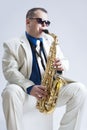 Music Ideas and Concepts. Handsome and Expressive Caucasian Music Player Posing In Sunglasse With Saxophone Against White