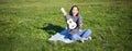 Music and instruments. Portrait of cute asian girl shows her white ukulele, plays in park while sitting relaxed on Royalty Free Stock Photo