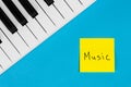 Music keys and paper reminder with word Music on a blue background, top view.