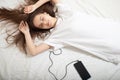 Music Lifestyle. Girl in headphones with a phone with closed eyes lies on the bed