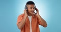 Music, man and dancing with headphones and studio with radio and audio app with blue background. Tech, smile and sound