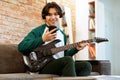 Cheerful Asian Teen Posing With Electric Guitar, Holding Smartphone Indoors Royalty Free Stock Photo