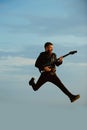 Music is so much fun. Bearded man jump with guitar on blue sky. Hipster guitarist with beard on excited face play in Royalty Free Stock Photo