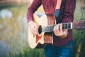 Music in nature, Man playing an acoustic guitar in meadow