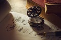 Music notes and old book with pocket watch on wooden table background in morning light. Royalty Free Stock Photo