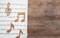 Music notes with sheet on wooden background, flat lay. Royalty Free Stock Photo