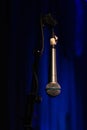 Microphone close hanging off microphone stand with blue background