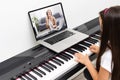 A little girl learns to play the piano from video lessons. Online distance learning during covid-19 Royalty Free Stock Photo