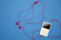 Music player with red earphone on blue paper background. Royalty Free Stock Photo