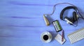 Music or podcast background with stylish headphones,vintage microphone,coffee and computer keyboard on blue table, top view,flat