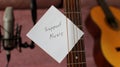 Support Music Note Attached to Guitar Strings in Home Studio of Indie Musician