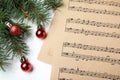 Music sheets near fir tree branches with Christmas balls on white background, flat lay Royalty Free Stock Photo