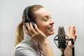 Music, show business, people and voice concept - singer with headphones and microphone singing a song in recording studio,