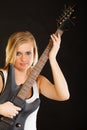 Blonde woman holding electric guitar, black background