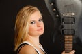 Blonde woman holding electric guitar, black background