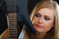 Blonde woman holding electric guitar, black background