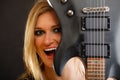 Blonde woman holding electric guitar, black background